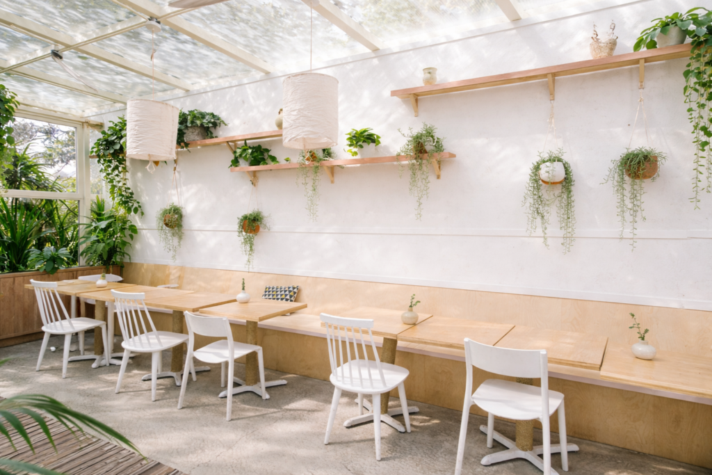 Outdoor cafe seating with modern wooden tables and chairs in a bright, aesthetic setting